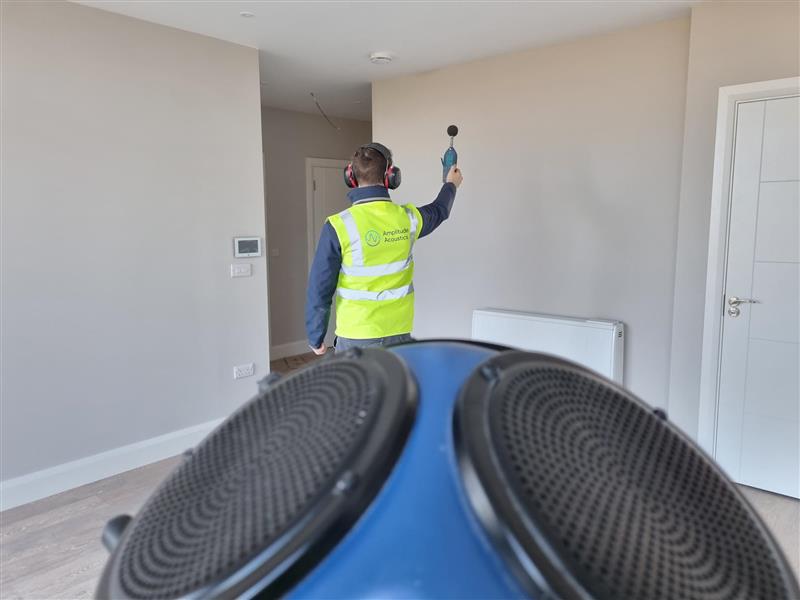 An Amplitude Acoustics engineer conducting sound insulation testing in an apartment